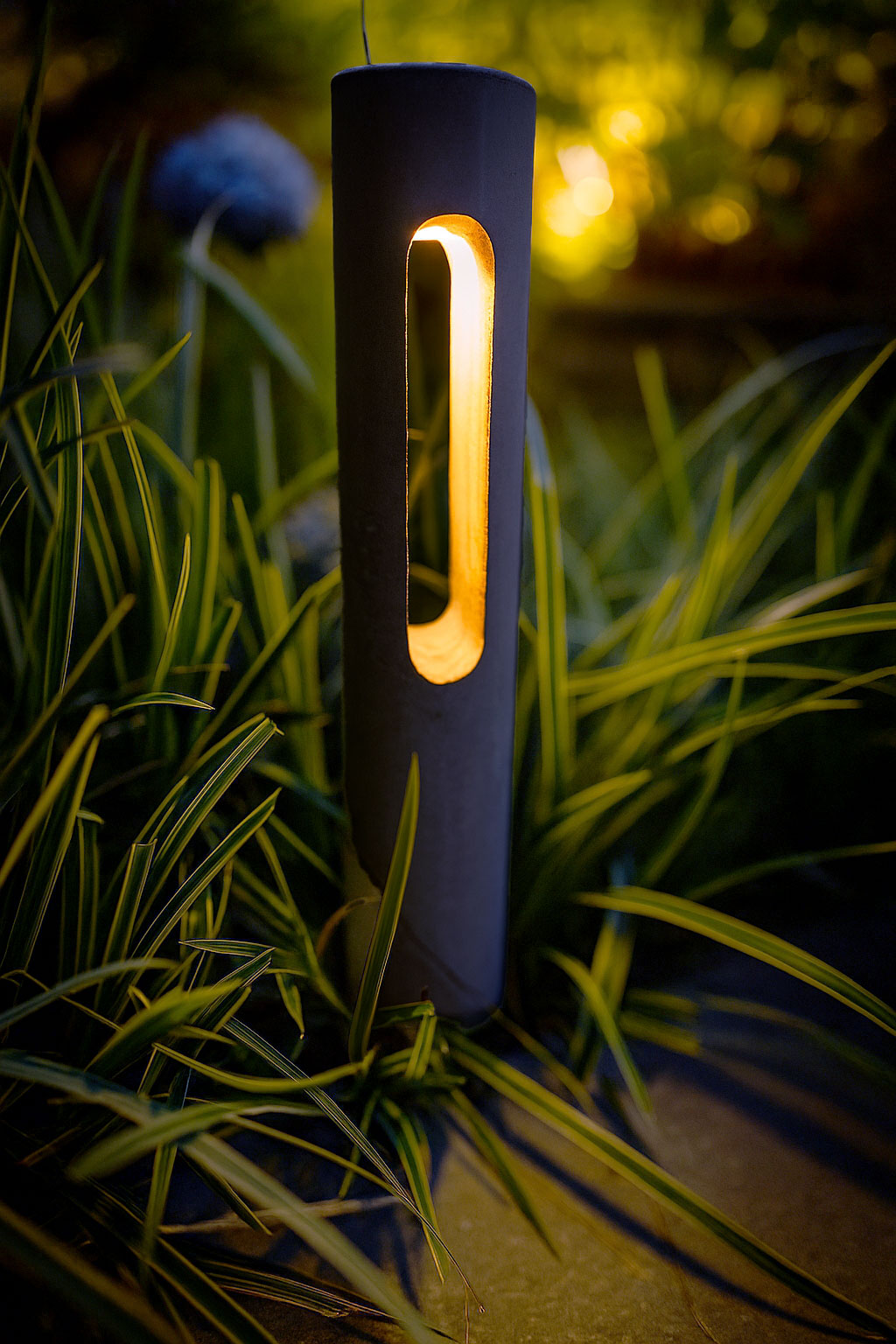 Black outdoor lamp with warm glow in grass