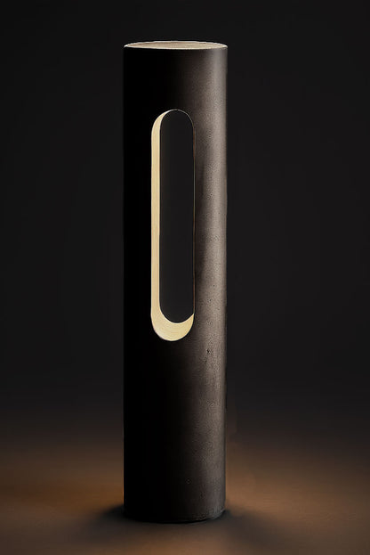 Cylindrical concrete light with a handle on a dark background
