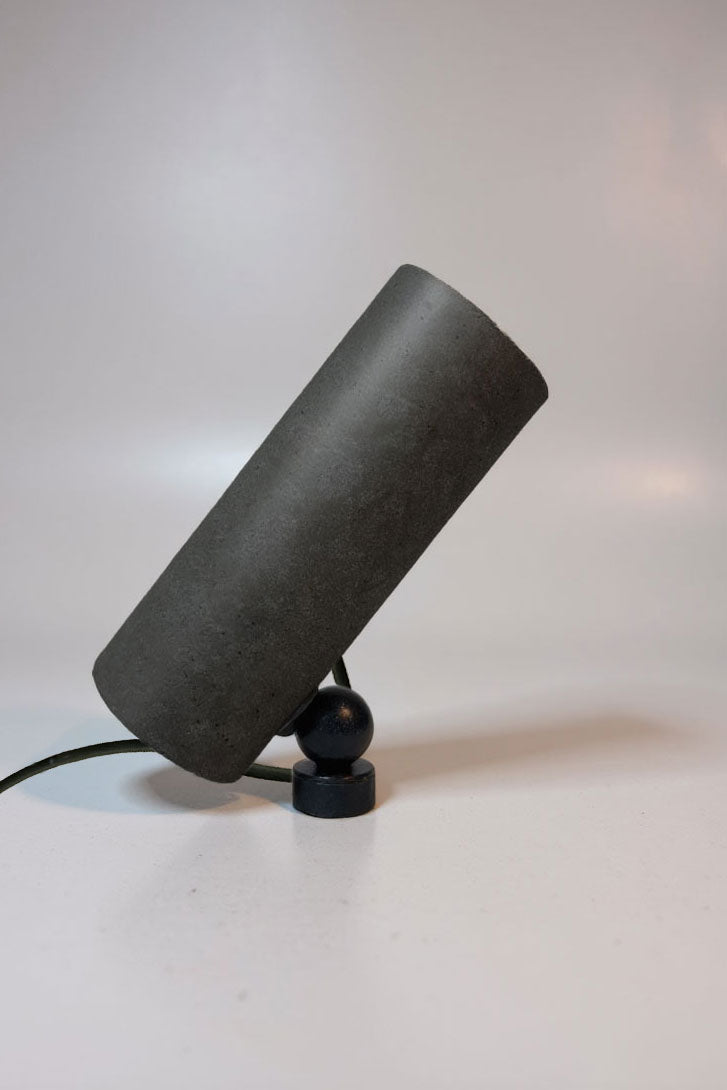 Black cylindrical lamp on a white surface with a light gray background