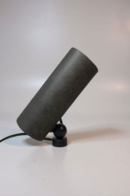 Black cylindrical lamp on a white surface with a light gray background