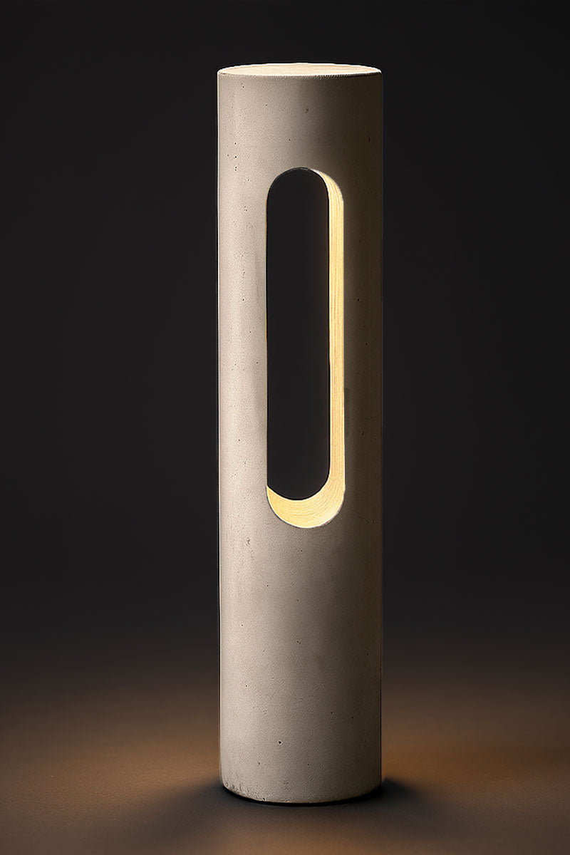 Cylindrical concrete lamp with a rectangular cutout on a dark background